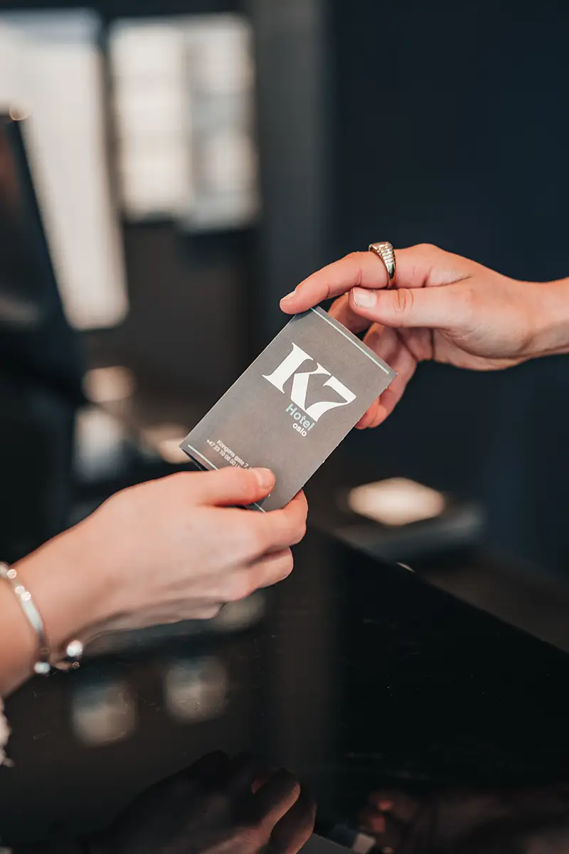 Hands exchanging key card in the reception of K7 Hotel Oslo.